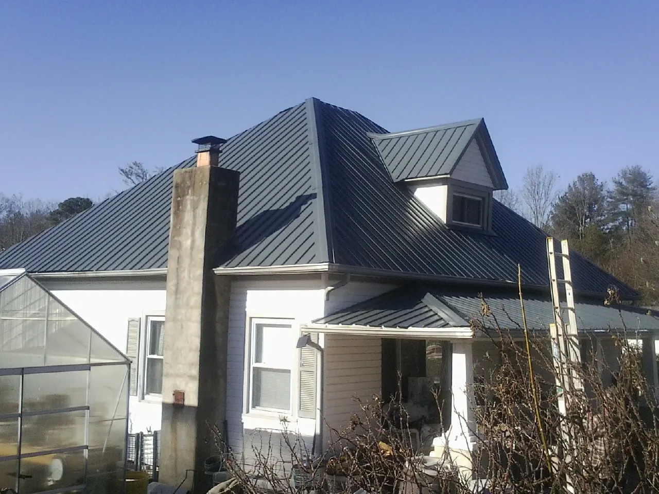 Dark blue standing seam metal roof on a white farmhouse with dormer — Slate & Tile Roof Repair by Roofing Brothers in Cayuta