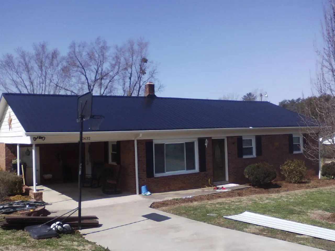 Finished dark blue metal roof on a brick ranch with a carport in Cayuta