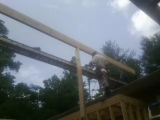 Carpenter setting a ridge beam over a new addition frame — Ice Dam Removal by Roofing Brothers in Cayuta