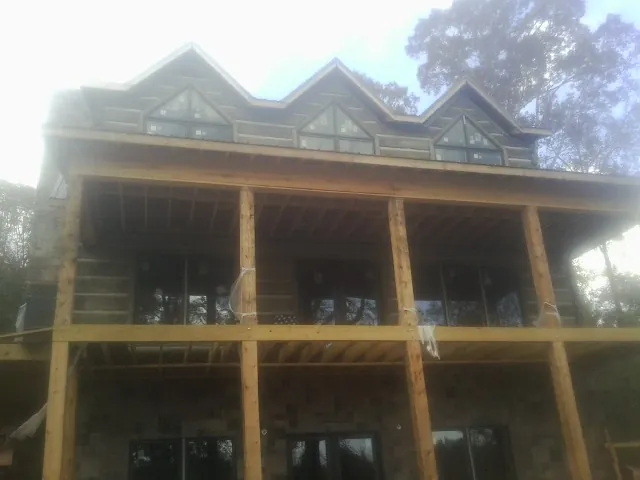 Dormers and porch framing on a large log home under construction — Roof Coating work by our crew in Cayuta