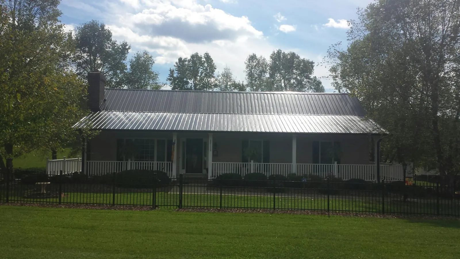 Gray metal roof on a brick ranch with a full width front porch — Gutter Guard Installation work by our crew in Cayuta