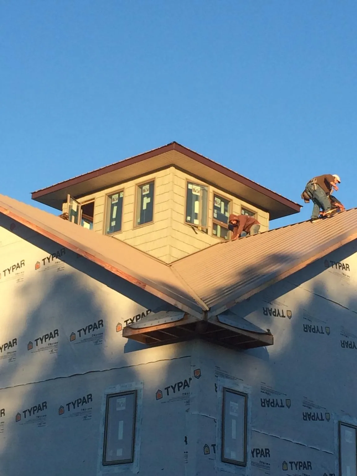Roofers working around a rooftop cupola on a new metal roof at sunset — Roof Waterproofing in Cayuta by Roofing Brothers